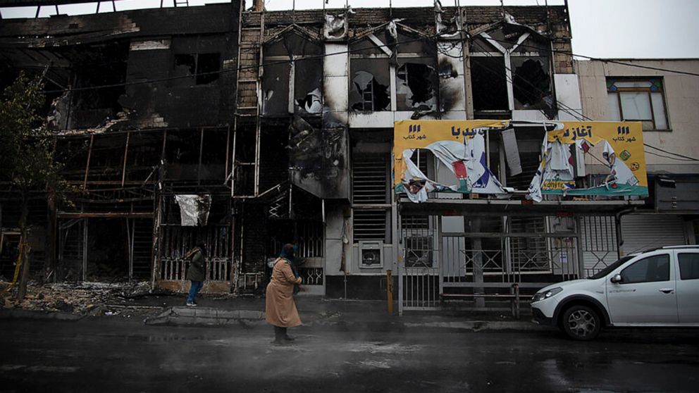 PHOTO: In this photo taken Nov. 18, 2019, and released by Iranian Students' News Agency, people walk past buildings which burned during protests that followed the authorities' decision to raise gasoline prices, in Karaj, west of the capital Tehran, Iran.