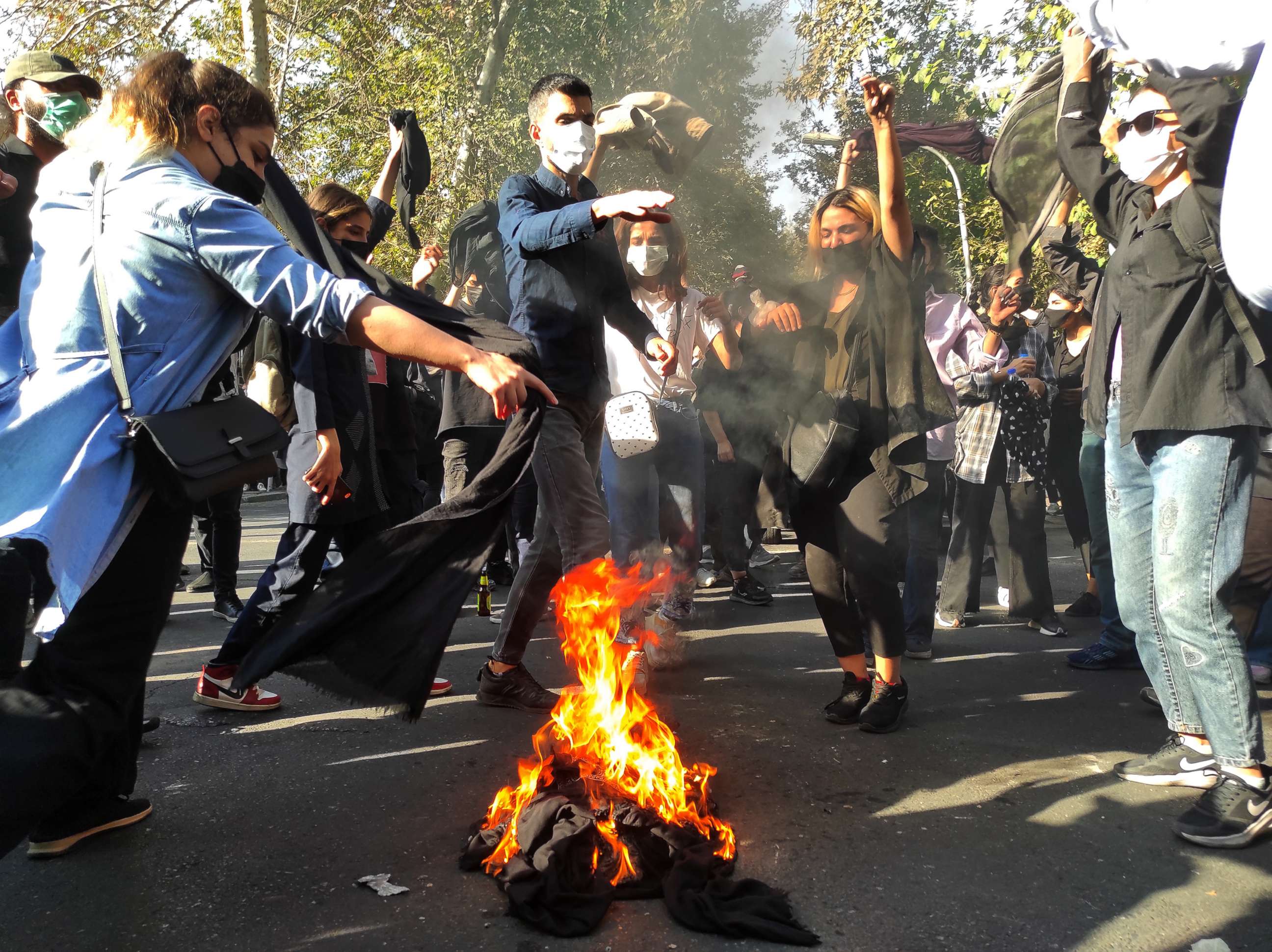 PHOTO: Iranian protesters set their scarves on fire while marching down a street in Tehran on Oct. 1, 2022.