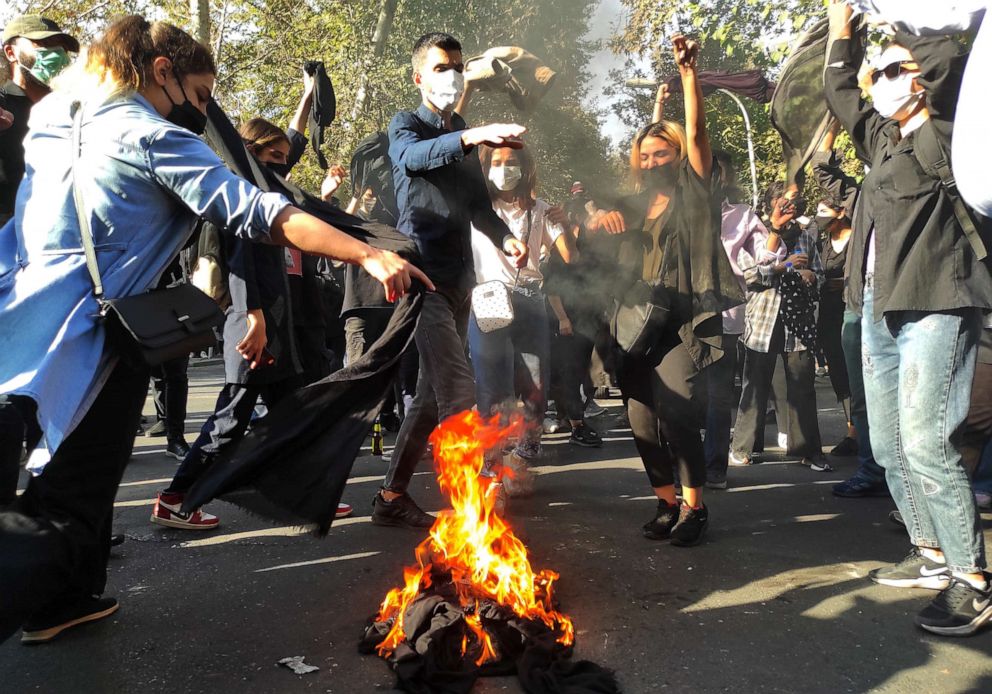 PHOTO: Iranian protesters set their scarves on fire while marching down a street on Oct. 1, 2022 in Tehran, Iran.