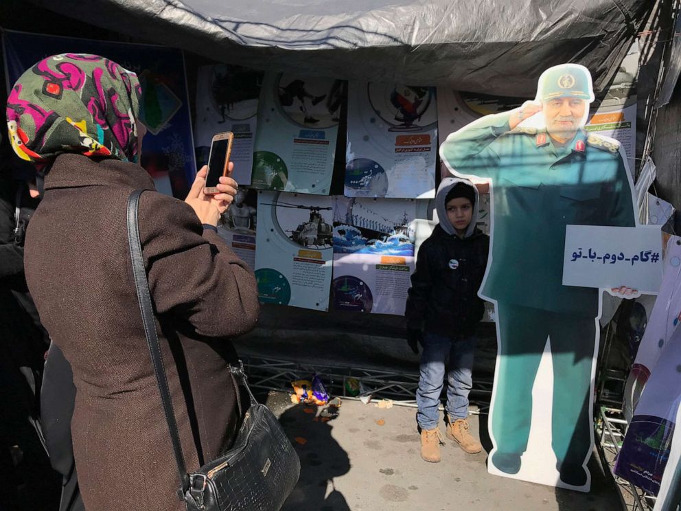 PHOTO: A woman takes a photo of a child next to a cardboard image of General Qassem Soleinani at a rally celebrating the 41st anniversary of the Islamic Revolution in Tehran, Iran.