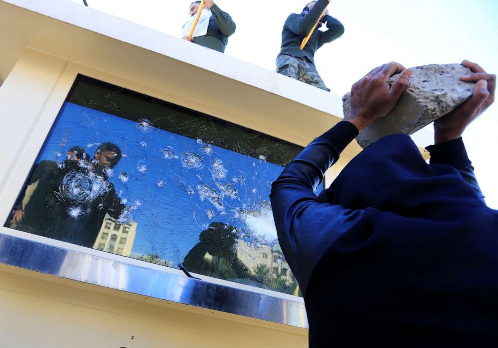 PHOTO: A protester holds a rock to break a glass window of a security guard building of the U.S. Embassy, as people gather to condemn air strikes on bases belonging to Hashd al-Shaabi (paramilitary forces), in Baghdad, Dec. 31, 2019.