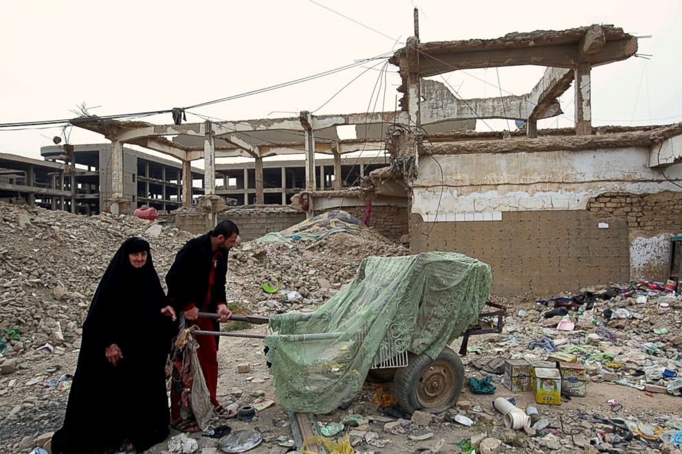 PHOTO: Homeless Iraqi people push their belongings through the rubble of al-Rashid military base belonging to the former Iraqi army in Baghdad, Iraq, Feb. 12, 2018. 