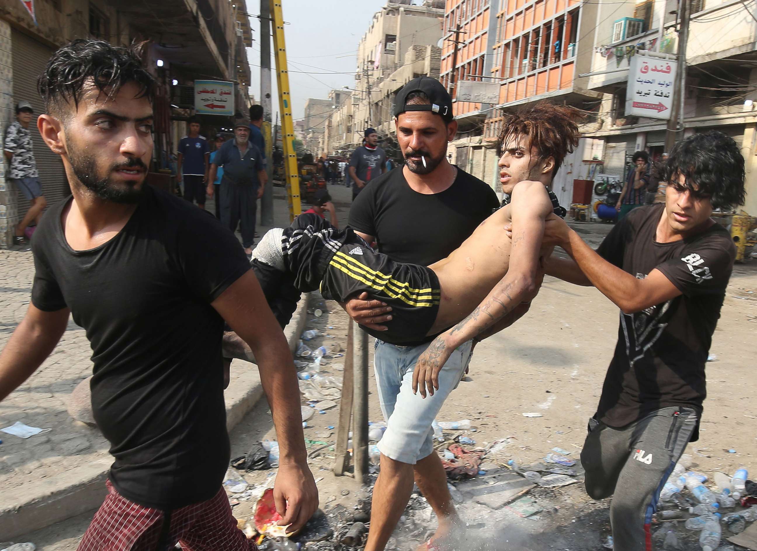 PHOTO: People carry away a protester injured during clashes with riot police in the Iraqi capital Baghdad's central Tahrir Square, Oct. 3, 2019.