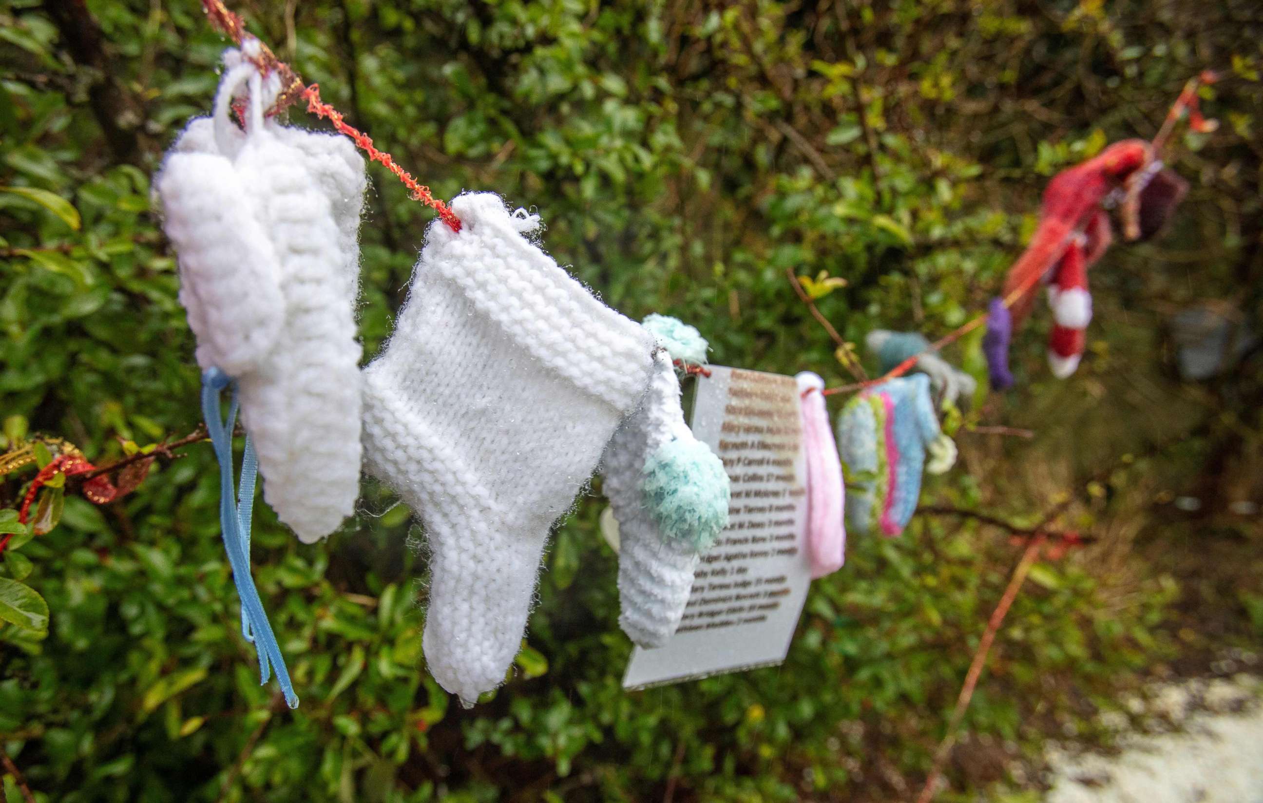 PHOTO: Baby socks and hearts are pictured at a shrine in Tuam, County Galway in January 13, 2021, erected in memory of up to 800 children who were allegedly buried at the site of the former home for unmarried mothers run by nuns. 