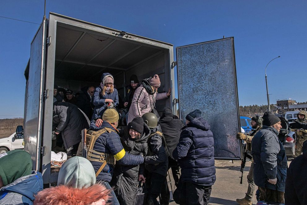 FOTOĞRAF: Ukrayna ordusu mensupları, 10 Mart 2022'de Ukrayna'nın Kiev bölgesine bağlı Irpin kasabasından kaçabilecekleri bölgeye geldikten sonra İrpin'den tahliye edilen sakinlerin kamyondan inmelerine yardım ediyor.