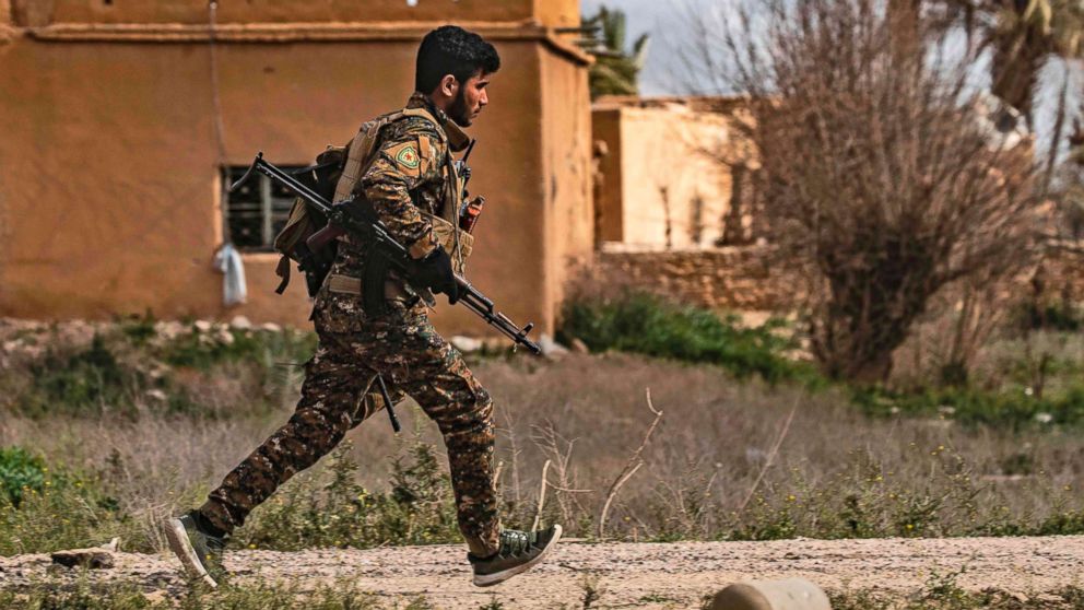 PHOTO: A member of the Syrian Democratic Forces (SDF) runs for cover during shelling on the Islamic State group's last holdout of Baghouz, in the eastern Syrian Deir Ezzor province, March 3, 2019.