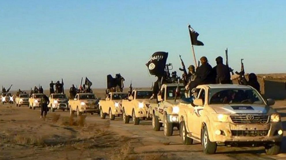 PHOTO: In this undated file photo released online in the summer of 2014  which has been verified and is consistent with other AP reporting, ISIS militants hold up their weapons and wave flags in a convoy on a road leading to Iraq, in Raqqa, Syria.
