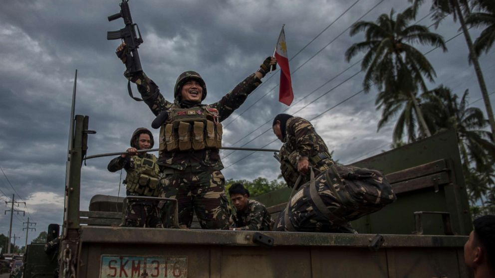 PHOTO: A government soldier waving the Philippine flag as they get ready to leave the battle against IS-inspired militants, Oct. 20, 2017, in Saguiaran town in Lanao del Sur, southern Philippines.
