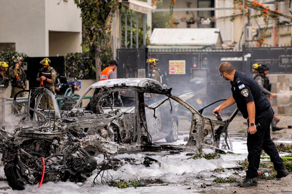 PHOTO: Israeli police inspect the husk of a destroyed vehicle at the site of a projectile impact from an Iranian strike in southern Tel Aviv on March 15, 2026.