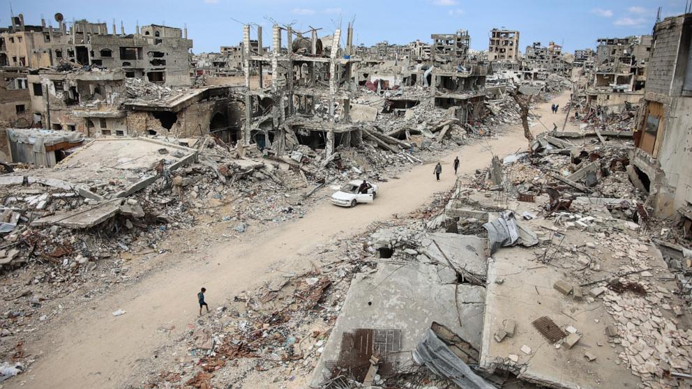 PHOTO: Displaced Palestinians walk on a dirt road lined with building rubble in the Shujaiya neighborhood of Gaza City, Oct. 7, 2024.