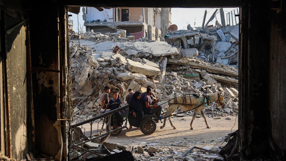 PHOTO: Palestinians make their way past destroyed buildings in Khan Yunis, June 20, 2024.