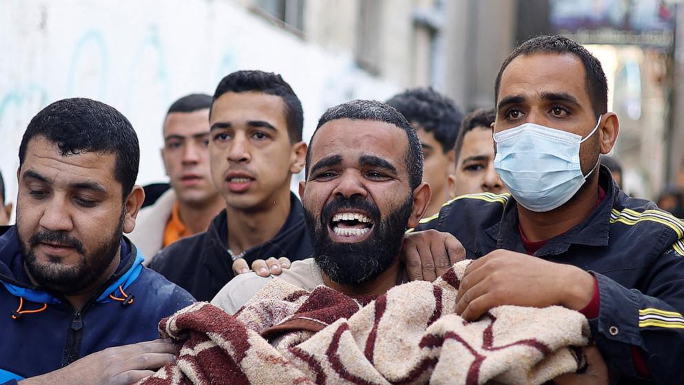 PHOTO: A Palestinian man carries a casualty at the site of Israeli strikes on houses in Rafah, in the southern Gaza Strip, Dec. 7, 2023. 