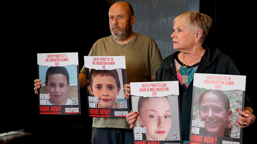 PHOTO: David and Varda Goldstein pose for a picture while holding-up photos of their 3 grandchildren, Gal, Tal and Agam as they await more details on the hostages deal in a hotel on Nov. 22, 2023, in Tel Aviv, Israel. 