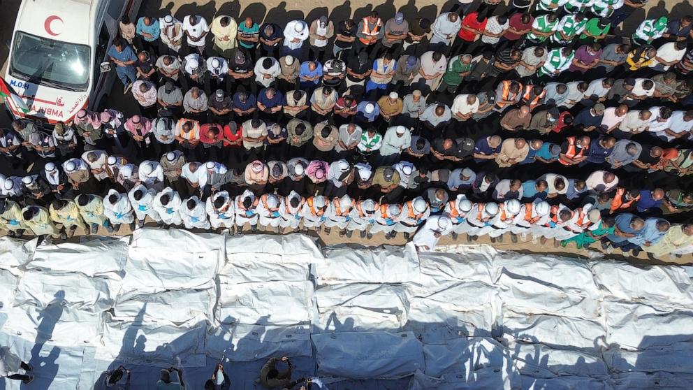 PHOTO: Medical teams pray beside the covered remains and bodies of unidentified Palestinians, returned by Israel, before their mass burial outside Nasser Hospital in Khan Yunis, southern Gaza Strip, October 22, 2025.