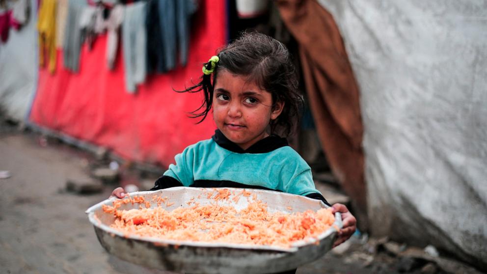 PHOTO: A Palestinian girl holds a plate of rice outside her tent at a refugee camp in Rafah in the southern Gaza Strip on Feb. 27, 2024, as battles between Israel and the Palestinian militant group Hamas continue.