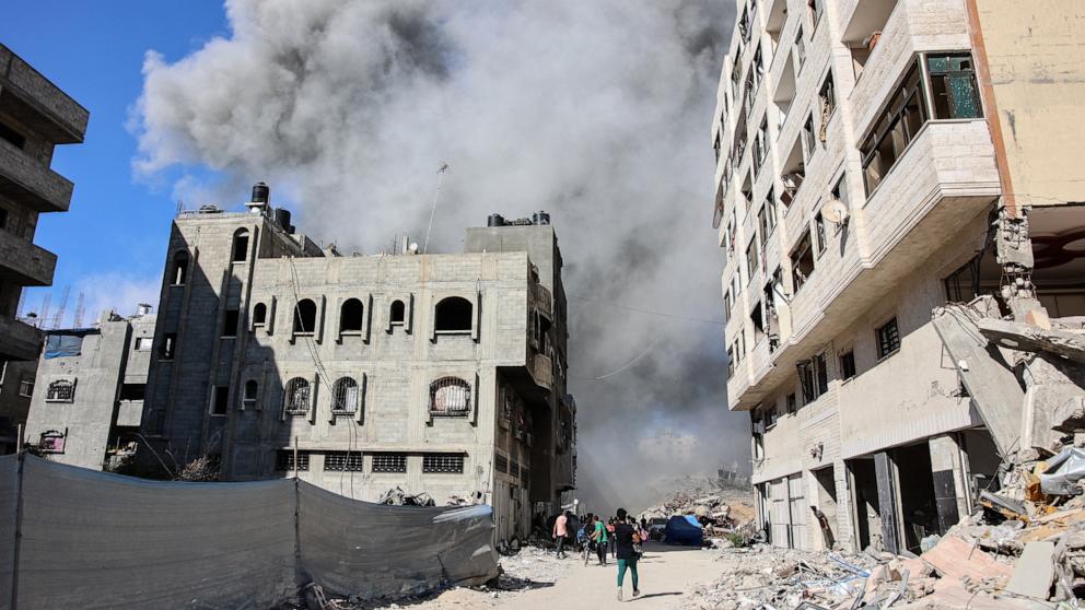 PHOTO: Palestinians watch as smoke rises from a building hit by an Israeli strike after a warning from the army to its occupants to evacuate the premises, in the Rimal neighborhood of central Gaza City, Aug. 21, 2024.