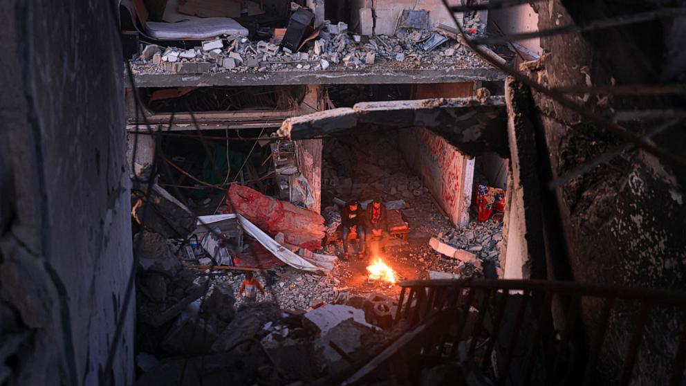 PHOTO: People sit around a campfire in the midst of destroyed buildings in the Khezaa district on the outskirts of the southern Gaza Strip city of Khan Yunis, Nov. 30, 2023. 