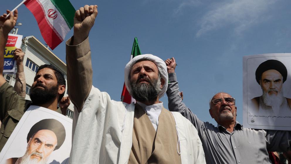PHOTO: An Iranian Shiite Muslim cleric raises a clenched fist as others carry pictures of Iran's late supreme leader Ayatollah Ruhollah Khomeini, during an anti-Israel demonstration after the Friday noon prayer in Tehran, Apr. 19, 2024. 