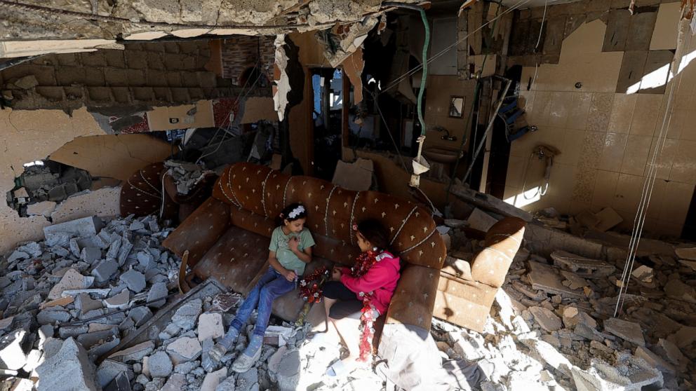 PHOTO: Palestinian girls sit on a couch at the remains of their house hit in Israeli strikes during the conflict, amid the temporary truce between Israel and the Palestinian Islamist group Hamas, in Khan Younis, in the southern Gaza Strip, Nov. 29, 2023. 