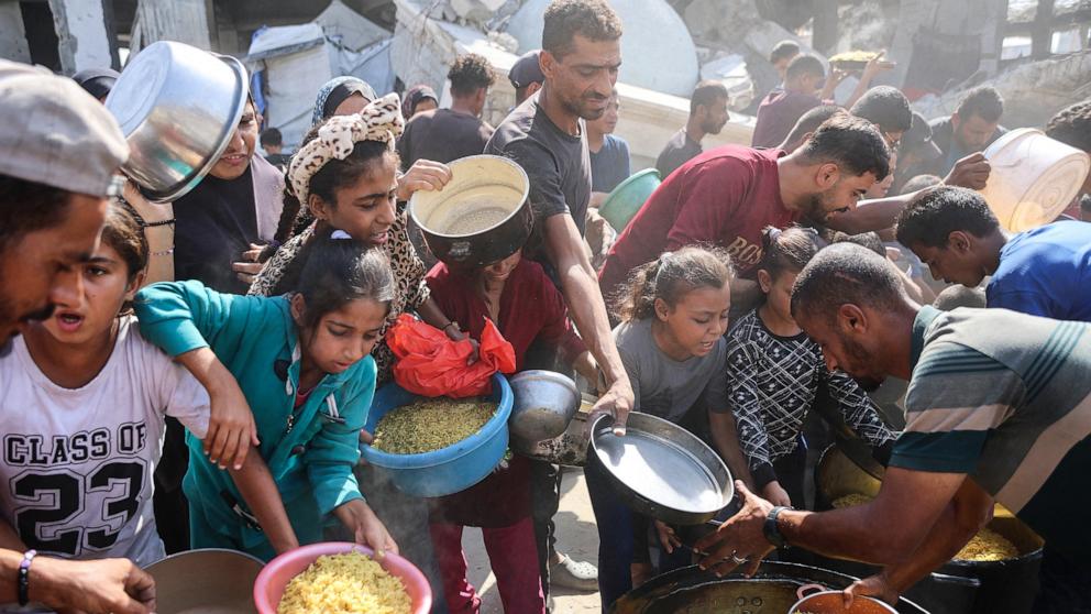 PHOTO: Displaced Palestinians gather to receive food portions outside the damaged Imam al Shafi'i Mosque, where families have taken shelter, in the Zeitoun neighbourhood of Gaza City, October 23, 2025.