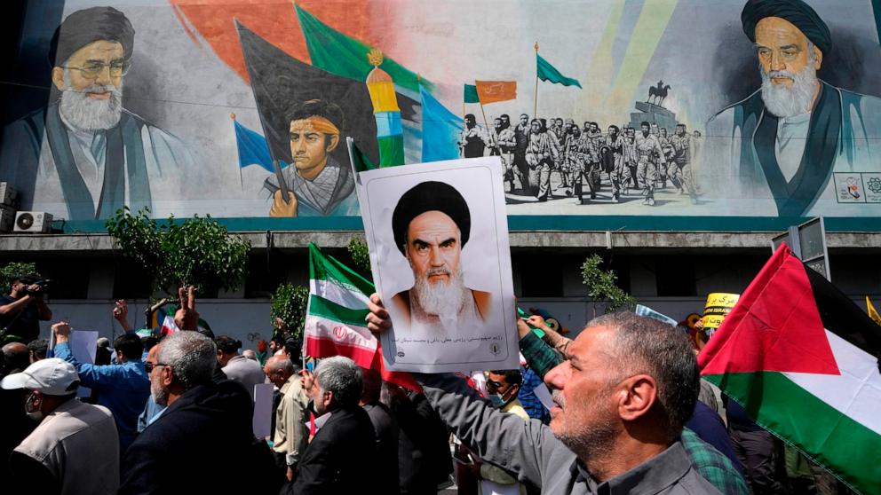 PHOTO: Iranian worshippers walk past a mural showing the late revolutionary founder Ayatollah Khomeini, Supreme Leader Ayatollah Ali Khamenei, and Basij paramilitary force, during an anti-Israeli protest after Friday prayers in Tehran, Apr. 19, 2024.