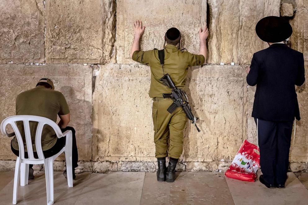 PHOTO: An Israeli soldier carrying a weapon and a religious Jewish man pray at the Western Wall in Jerusalem's Old City, Nov. 6, 2023.