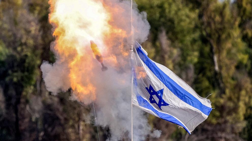 PHOTO: A mortar round flies past an Israeli flag waving atop an Israeli armored vehicle from a position along the border in southern Israel on Jan. 3, 2024.