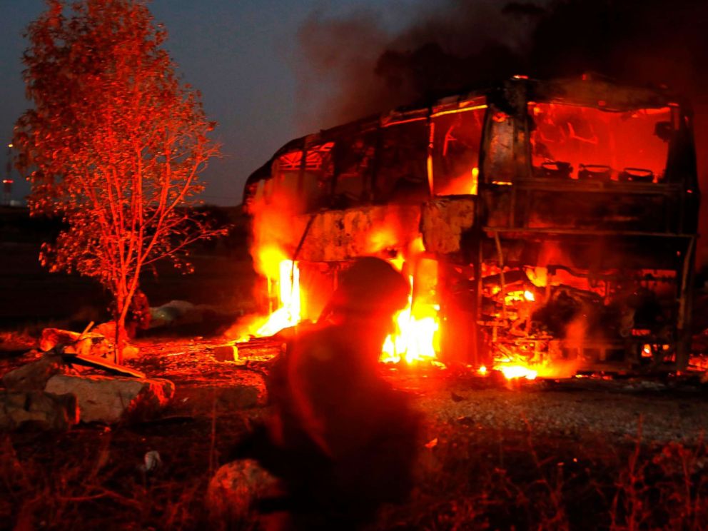 PHOTO: Israeli security forces and firefighters gather near a bus set ablaze after it was hit by a rocket fired from the Palestinian enclave, at the Israel-Gaza border near the kibbutz of Kfar Aza, on Nov. 12, 2018.