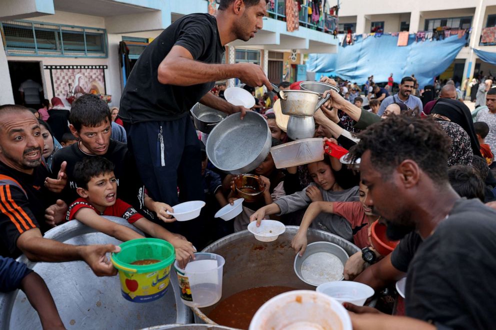 PHOTO: Palestinian children receive food at a UN-run school in Rafah, on the southern Gaza Strip on Oct. 23, 2023 amid ongoing battles between Israel and Hamas militants.