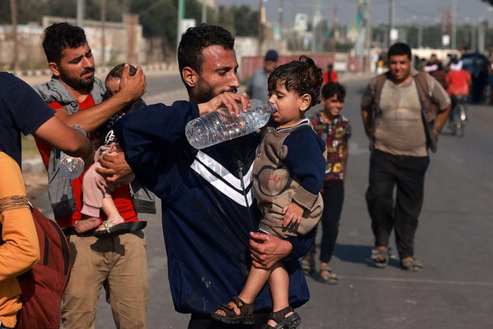 PHOTO: Men help toddlers to drink some water upon reaching the central Gaza Strip on foot via the Salah al-Din road on their way to the southern part of the Palestinian enclave on Nov. 5, 2023.