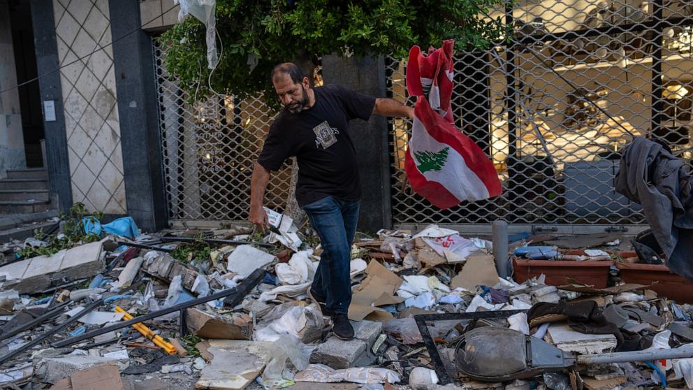 PHOTO: A man picks up a Lebanese flag from the rubble after an Israeli airstrike on an apartment block, Oct. 3, 2024, in Beirut, Lebanon.