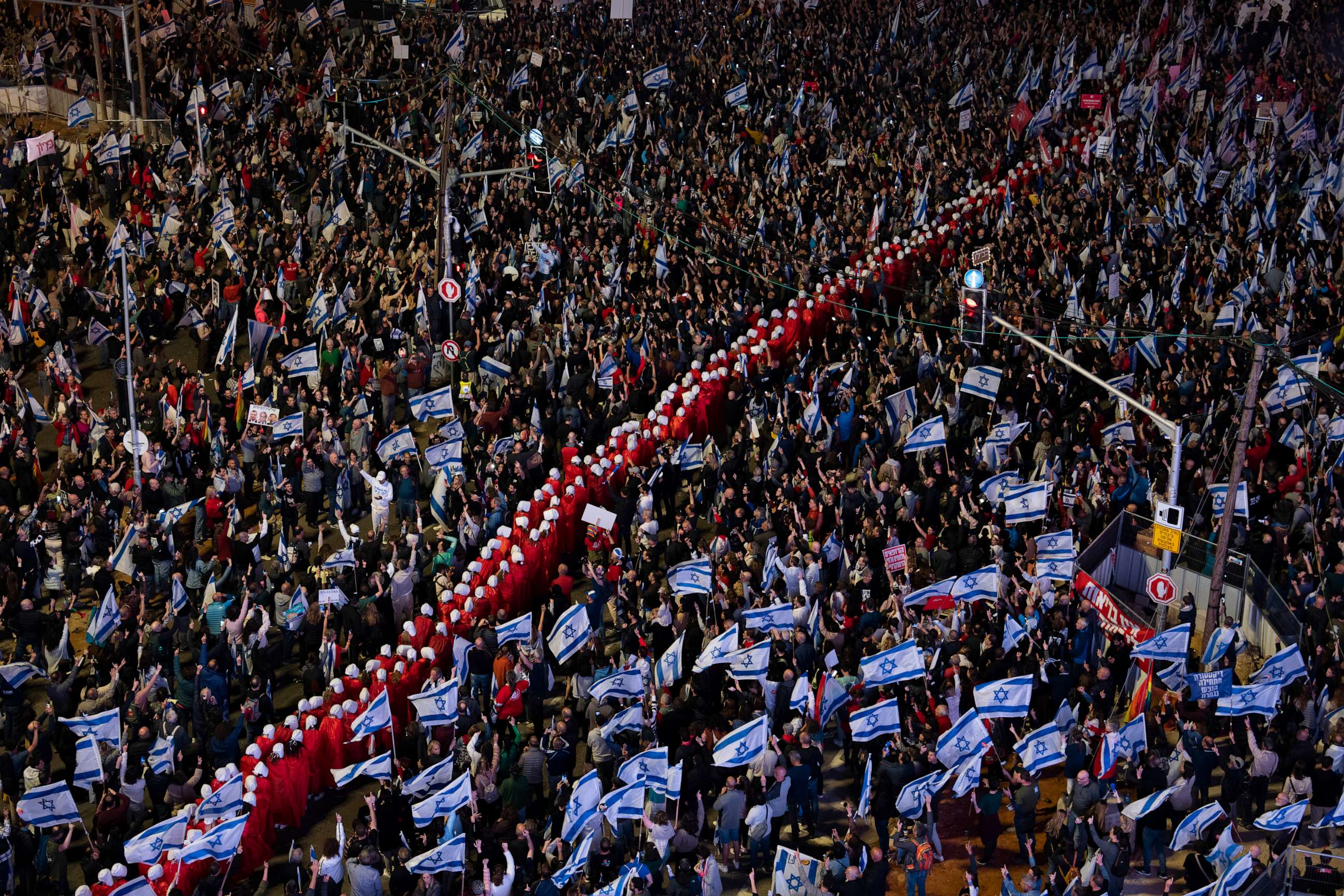 PHOTO: A line of protesters supporting women's rights, dressed as characters from The Handmaid's Tale series, and other Israelis protest against plans by Prime Minister Netanyahu's government to overhaul the judicial system in Tel Aviv, March 25, 2023.