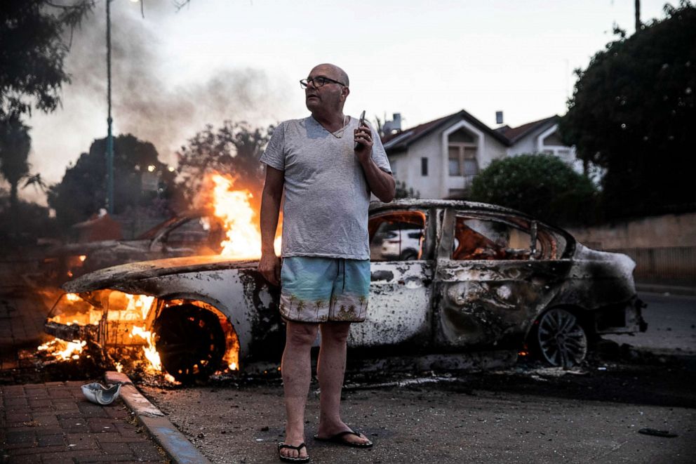 PHOTO: In this May 11, 2021, file photo, Jacob Simona stands by his burning car during clashes with Israeli Arabs and police in the Israeli mixed city of Lod, Israel.