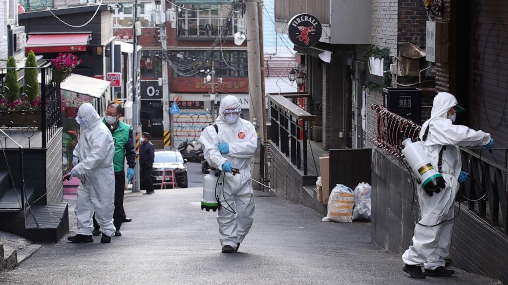 PHOTO: Health workers spray disinfectant on a street in the Itaewon district of Seoul on May 12, 2020. - South Korea's capital ordered the closure of all clubs and bars after a cluster of new cases were linked to a 29-year-old man. 