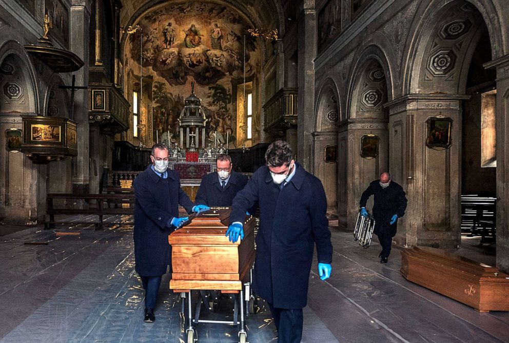 PHOTO: A coffin is brought for cremation in Vimercate, Italy, March 27, 2020. The Collegiate Church is being used as a waiting place for coffins of the dead from Covid-19.