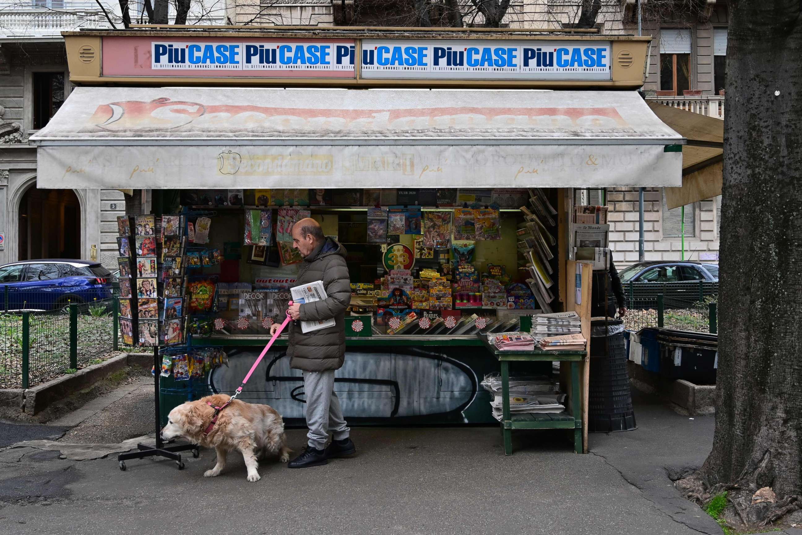 PHOTO: An elderly resident walks his dog and buys a newspaper at a newstand in Milan, March 12, 2020.