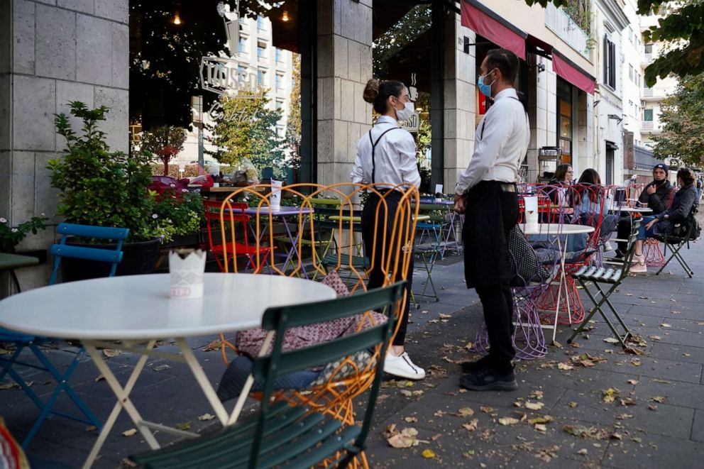 PHOTO: FILE - In this Oct. 13, 2020, file photo, a waiter and a waitress in masks wait for clients in Rome. 