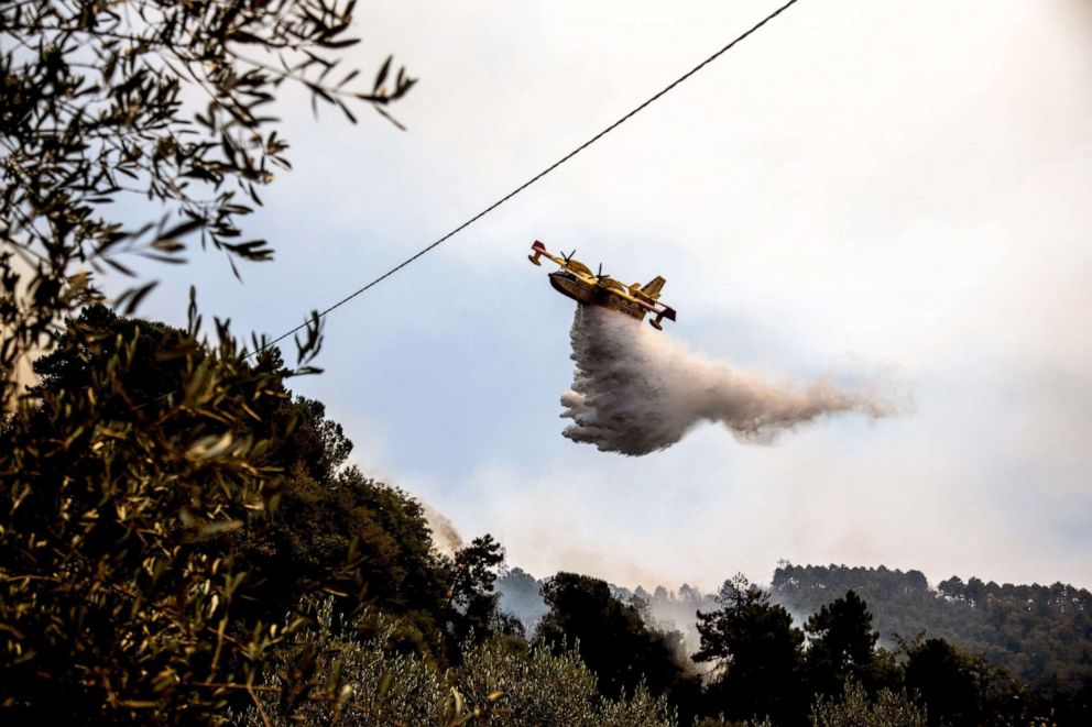 PHOTO: A Canadair aircraft drops water over a wildfire raging near the city of Massarosa, Italy, on July 20, 2022.
