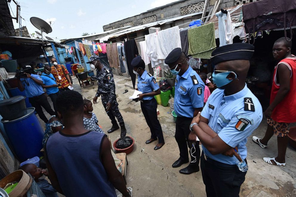 PHOTO: Residents listen on April 22, 2020, as Ivorian policemen talk about the use of protective masks against the spread of the COVID-19 coronavirus in the popular Attecoube district of Abidjan, Cote d'Ivoire.