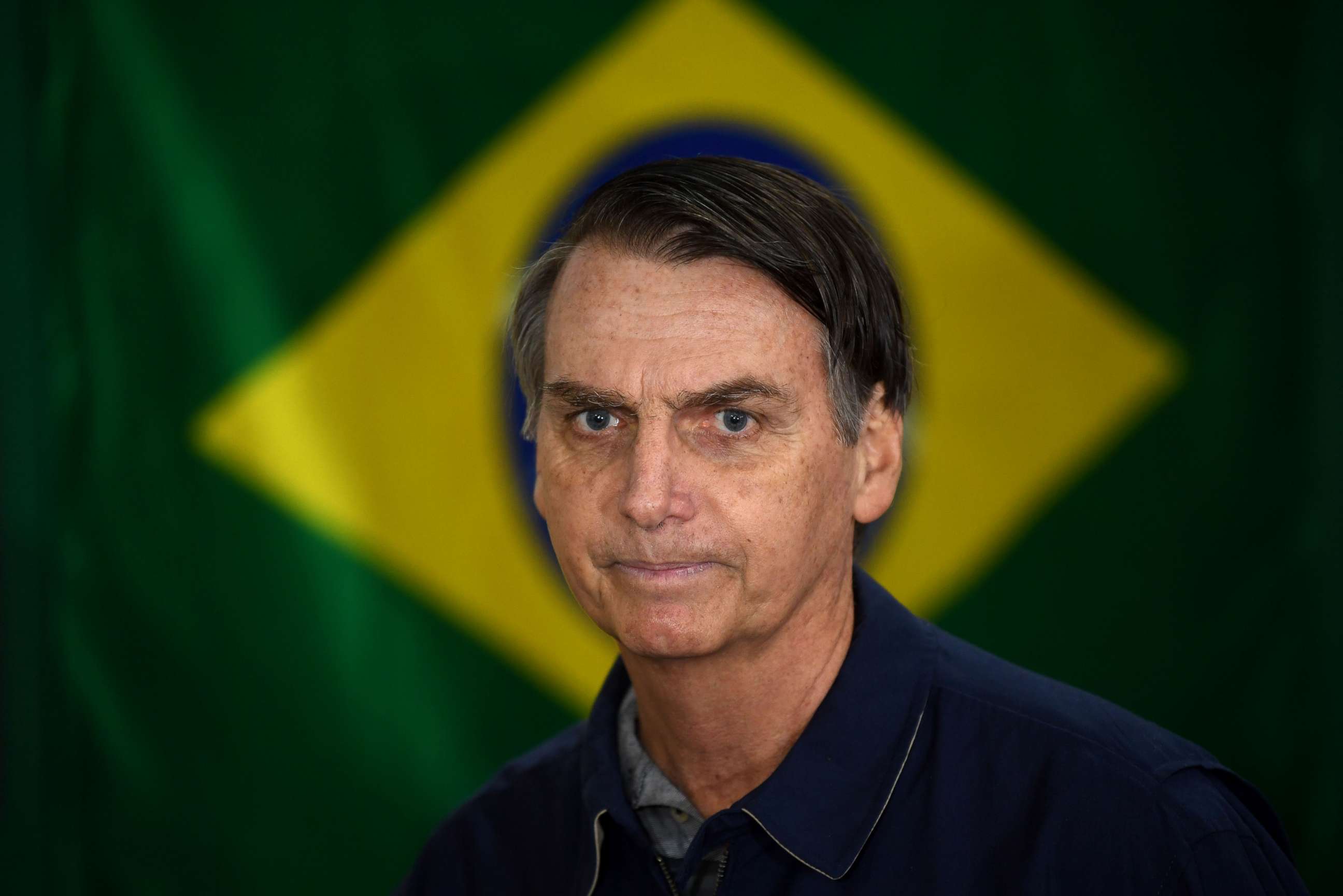 PHOTO: Brazil's right-wing presidential candidate for the Social Liberal Party (PSL) Jair Bolsonaro walks in front of the Brazilian flag as he prepares to cast his vote during the general elections, in Rio de Janeiro on Oct. 7, 2018.