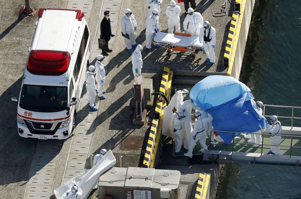 PHOTO: Officers in protective gear escort a person (under the blue sheet) who was on board the Diamond Princess cruise ship and tested positive for the new coronavirus, in Yokohama, Japan, Feb. 4, 2020.