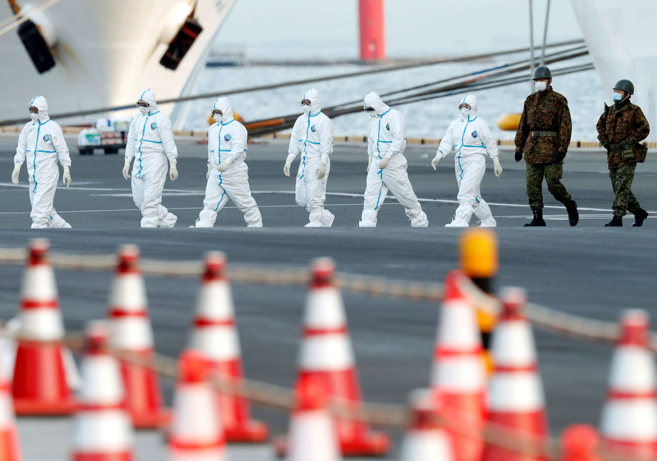 PHOTO: Workers and army officers wearing protective suits walk away from the Diamond Princess cruise ship, as they prepare to transfer passengers tested positive for the novel coronavirus, in the Japanese port of Yokohama, Feb. 10, 2020.