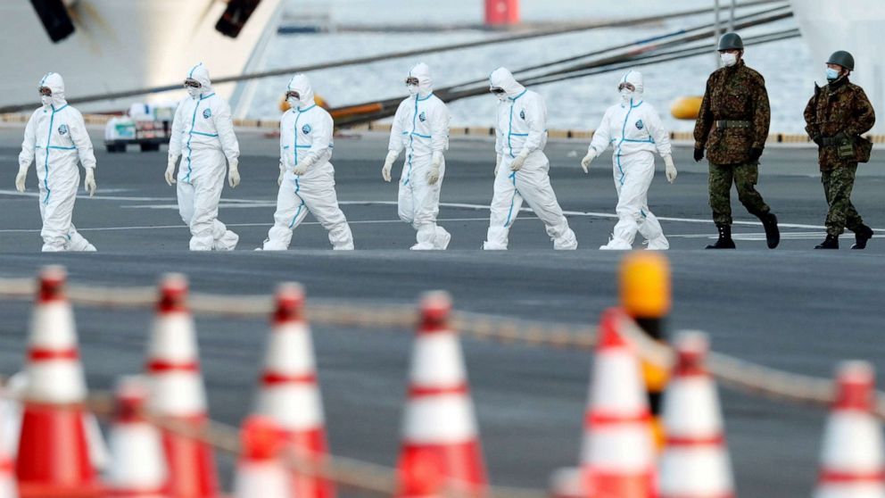 Workers and army officers wearing protective suits walk away from the Diamond Princess cruise ship, as they prepare to transfer passengers tested positive for the novel coronavirus, at Daikoku Pier Cruise Terminal in Yokohama, south of Tokyo, Japan, Feb. 10, 2020.Workers and army officers wearing protective suits walk away from the Diamond Princess cruise ship, as they prepare to transfer passengers tested positive for the novel coronavirus, at Daikoku Pier Cruise Terminal in Yokohama, south of Tokyo, Japan, Feb. 10, 2020. Kim Kyung Hoon/Reuters