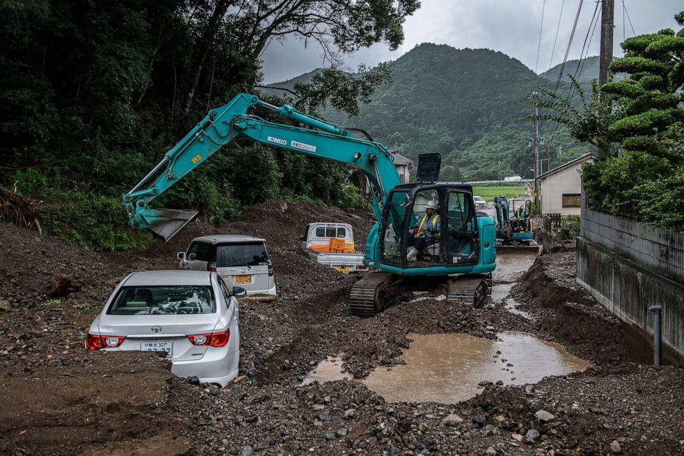PHOTO: A man operates an excavator to clear a road that was buried in mud by a landslide following torrential rain, on July 7, 2020, in Tsunagi, Japan.