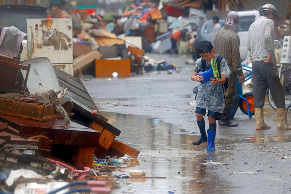 PHOTO: A boy walks along debris of household items piled up at the side of a road in Hitoyoshi city, Kumamoto prefecture, southwestern Japan, July 7, 2020.