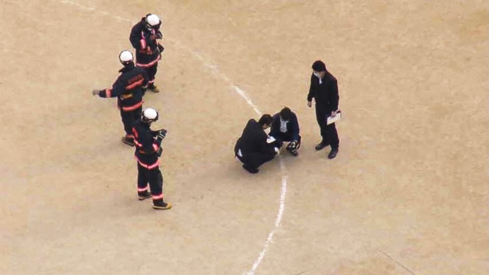 PHOTO: Investigators examine the site where the window landed on the school's sports field.