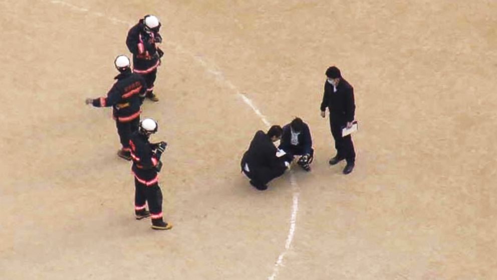 PHOTO: Investigators examine the site where the window landed on the school's sports field.