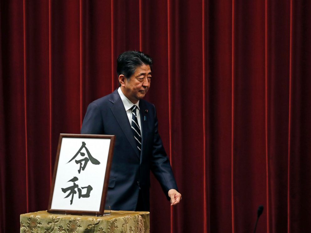 PHOTO: Japanese Prime Minister Shinzo Abe walks past the name of new era Reiwa on display at the Prime Ministers office in Tokyo, Monday, April 1, 2019.