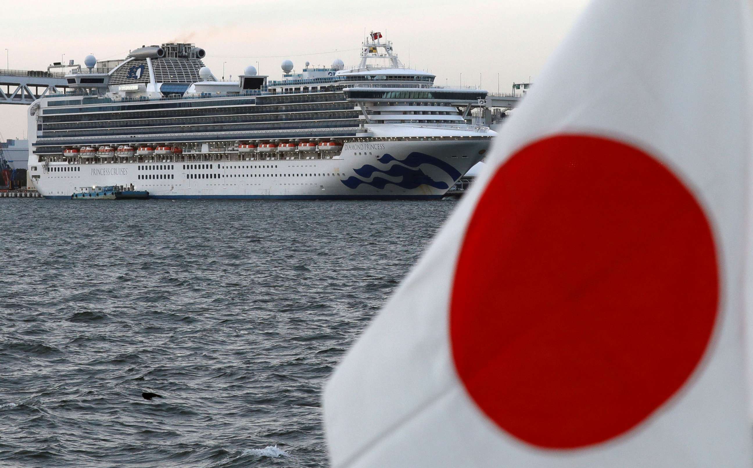 PHOTO: The Diamond Princess cruise ship is seen beside a Japanese flag as it lies at anchor at Daikoku Pier Cruise Terminal in Yokohama, south of Tokyo, Japanm Feb. 12, 2020.