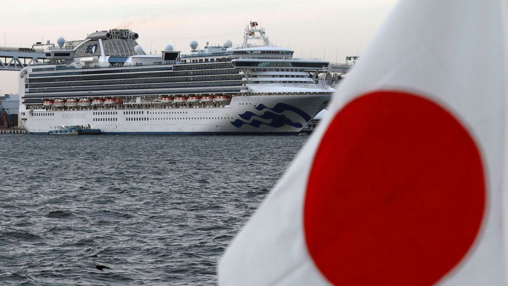 PHOTO: The Diamond Princess cruise ship is seen beside a Japanese flag as it lies at anchor at Daikoku Pier Cruise Terminal in Yokohama, south of Tokyo, Japanm Feb. 12, 2020.